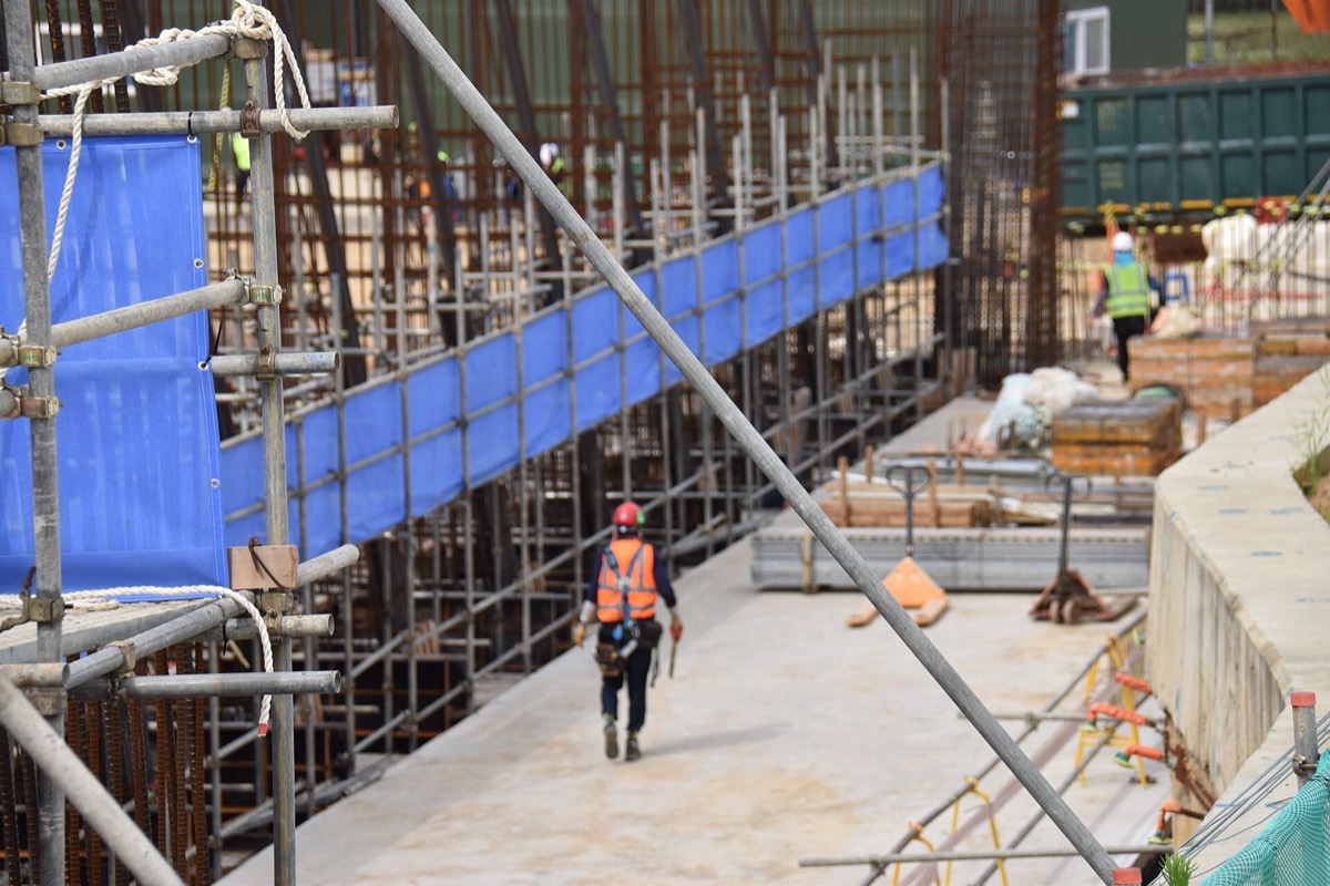 A construction worker in a safety vest crossing a building site